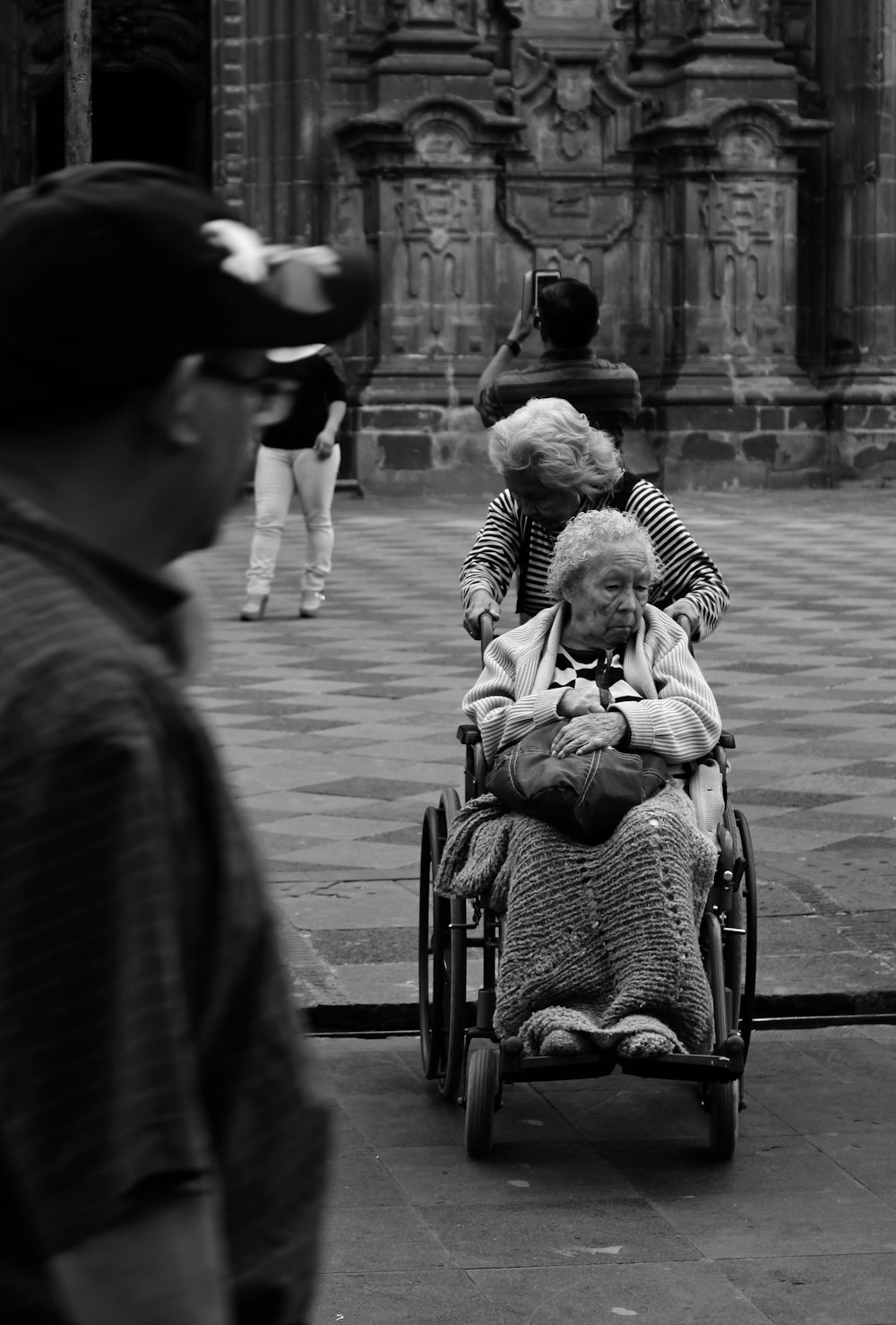 grayscale photography unknown person riding on wheelchair outdoors