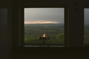 A candle with a full moon illustration on its label, placed on a windowsill with the night sky visible outside.