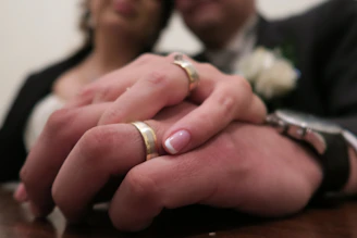 A close-up of intertwined hands of the couple, highlighting their wedding rings.