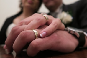 A close-up of intertwined hands wearing wedding rings.