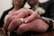 Close-up of a couple holding hands with wedding rings, surrounded by delicate floral details.