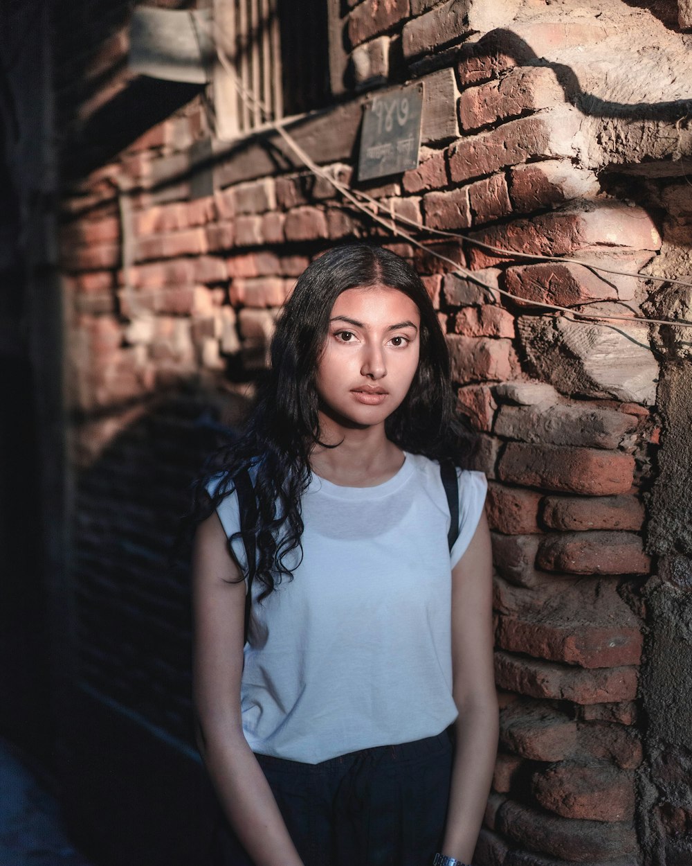 woman standing beside brown brick wall