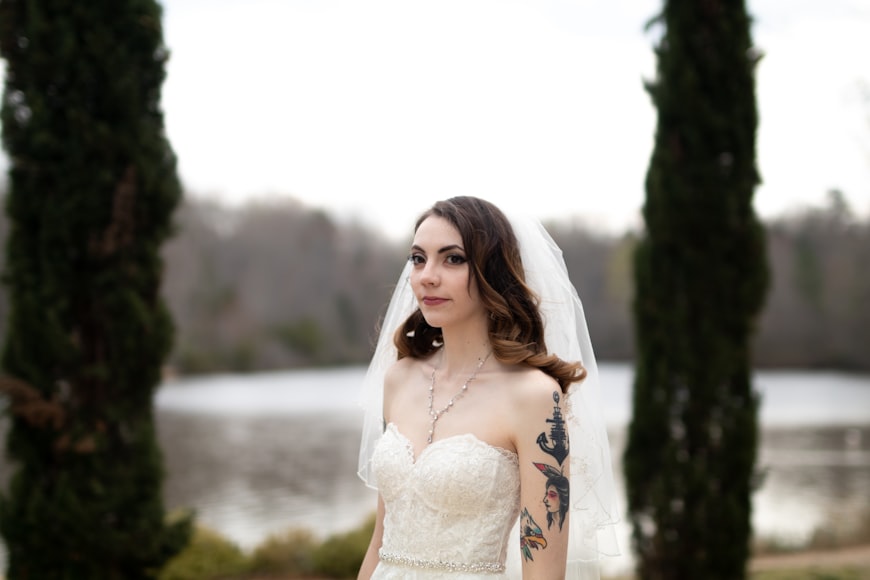 Une femme jeune, en robe de mariée et avec un voile. Elle est tatouée sur le bras