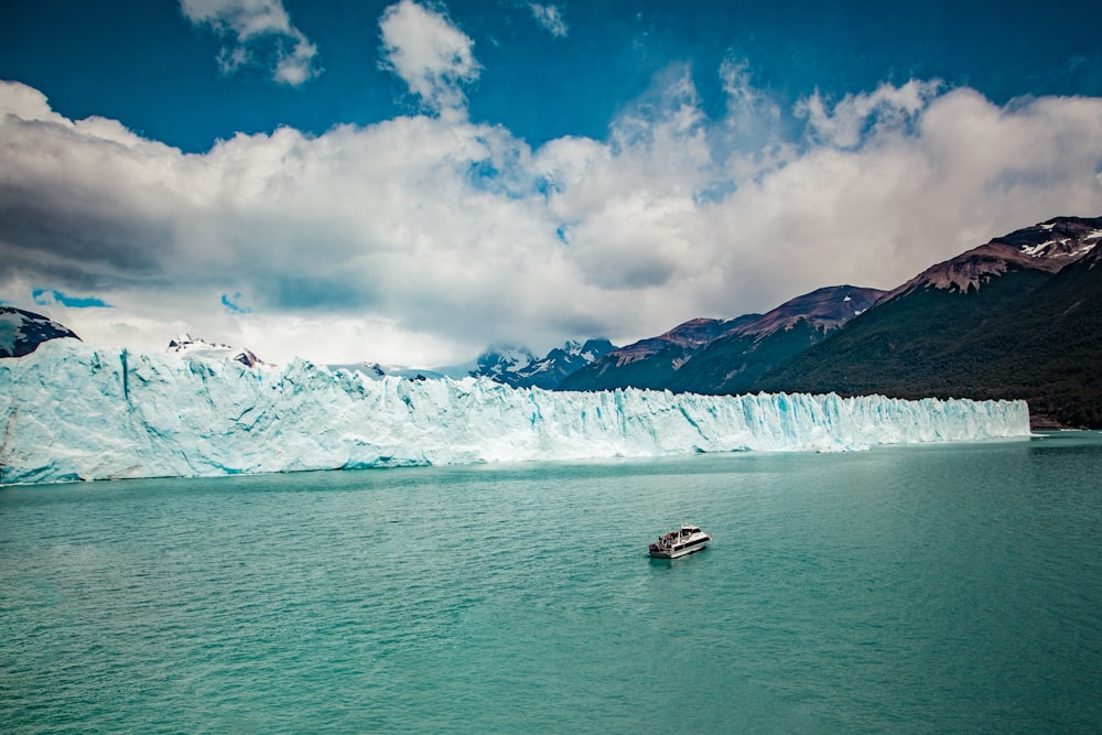 aerial photography of white boat on body of water beside ice block cliff during daytime