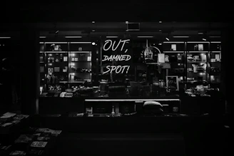 A moody, artfully lit display of Raven Rose Co.'s 3D printed bookish items and fidget toys arranged on a vintage wooden table.