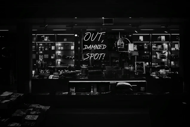 A moody, artfully lit display of Raven Rose Co.'s 3D printed bookish items and fidget toys arranged on a vintage wooden table.