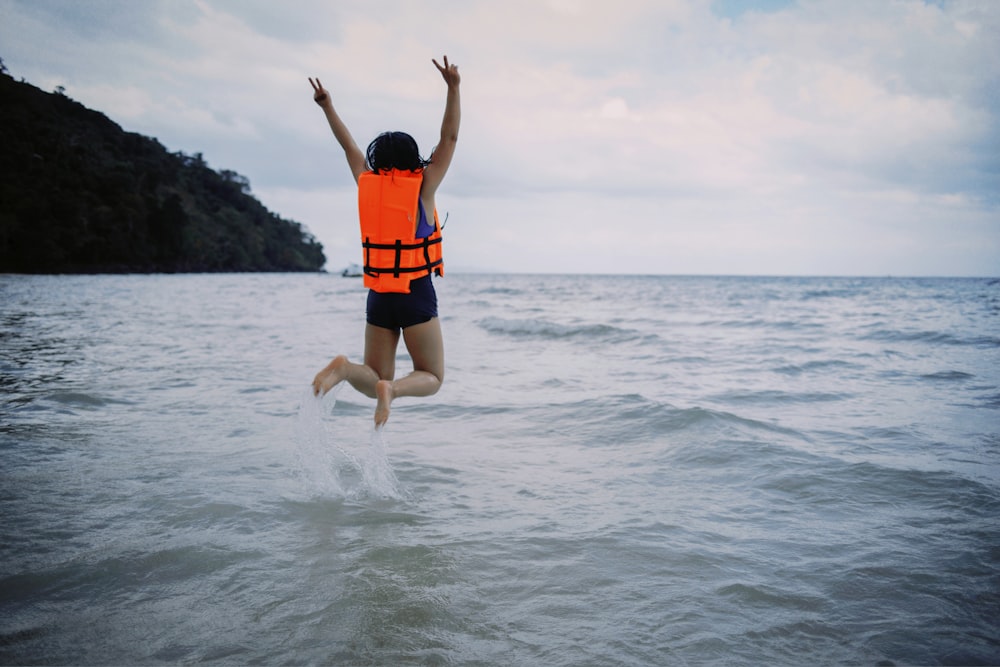 woman wearing life vest jumping into sea