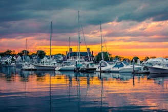 A picturesque sunset over a serene harbor filled with boats.