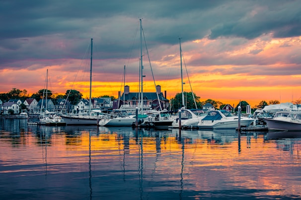 A picturesque sunset over a serene harbor filled with boats.