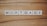 The word 'MORTGAGE' is spelled out using white letter tiles, each with black uppercase letters, arranged in a row on a wooden surface.