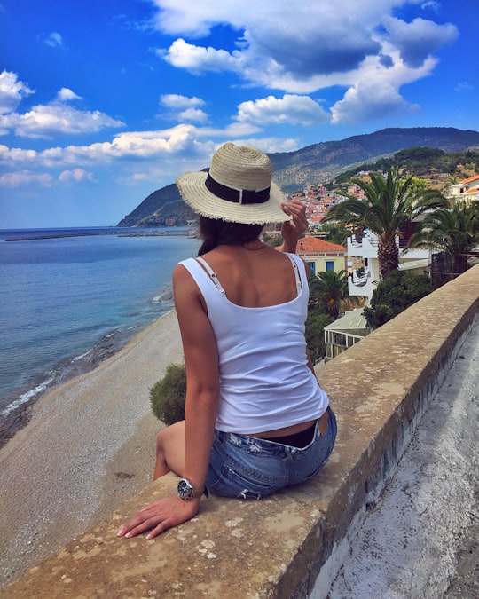 woman sitting on sea wall in Άγιος Ισίδωρος Greece