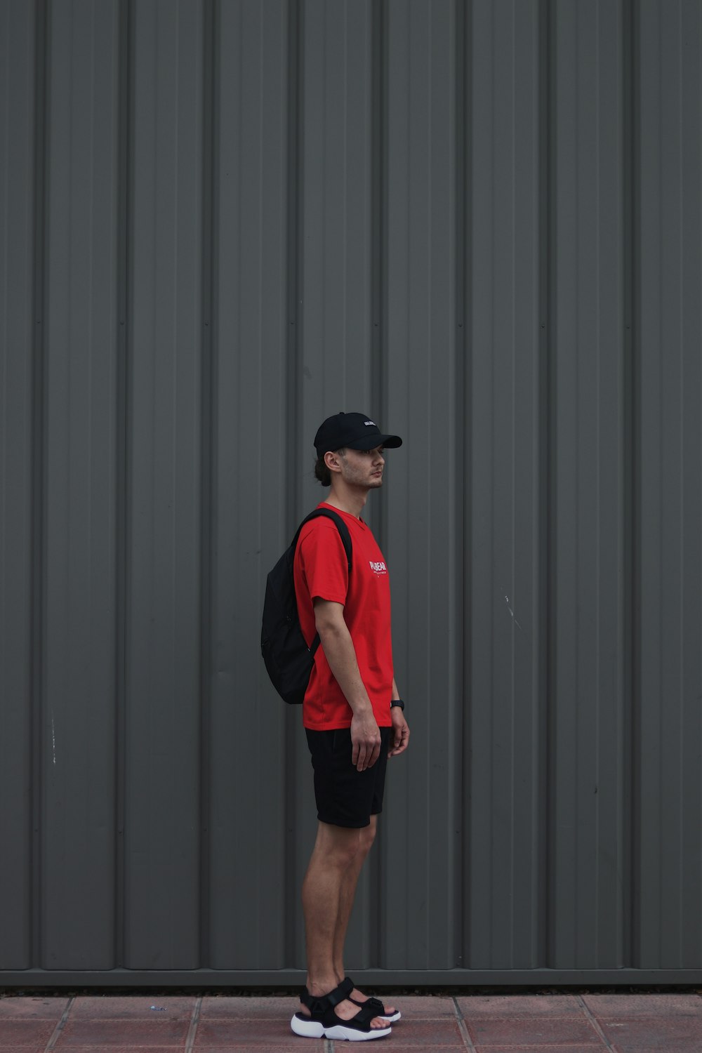 man standing beside gray wall during daytime