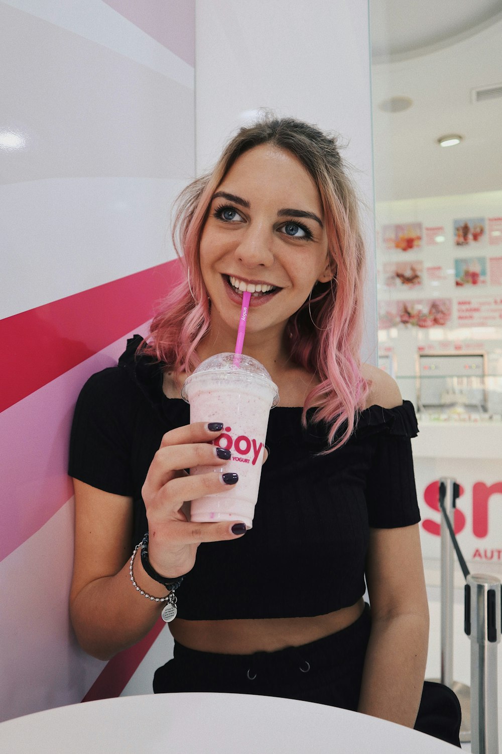 woman sipping drink from white disposable cup with lid and straw