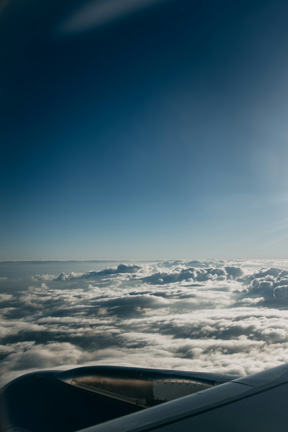 grey jetliner on flight over white clouds under clear blue sky