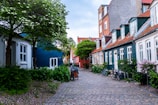 A quiet cobblestone street lined with colorful houses and blooming flowers.