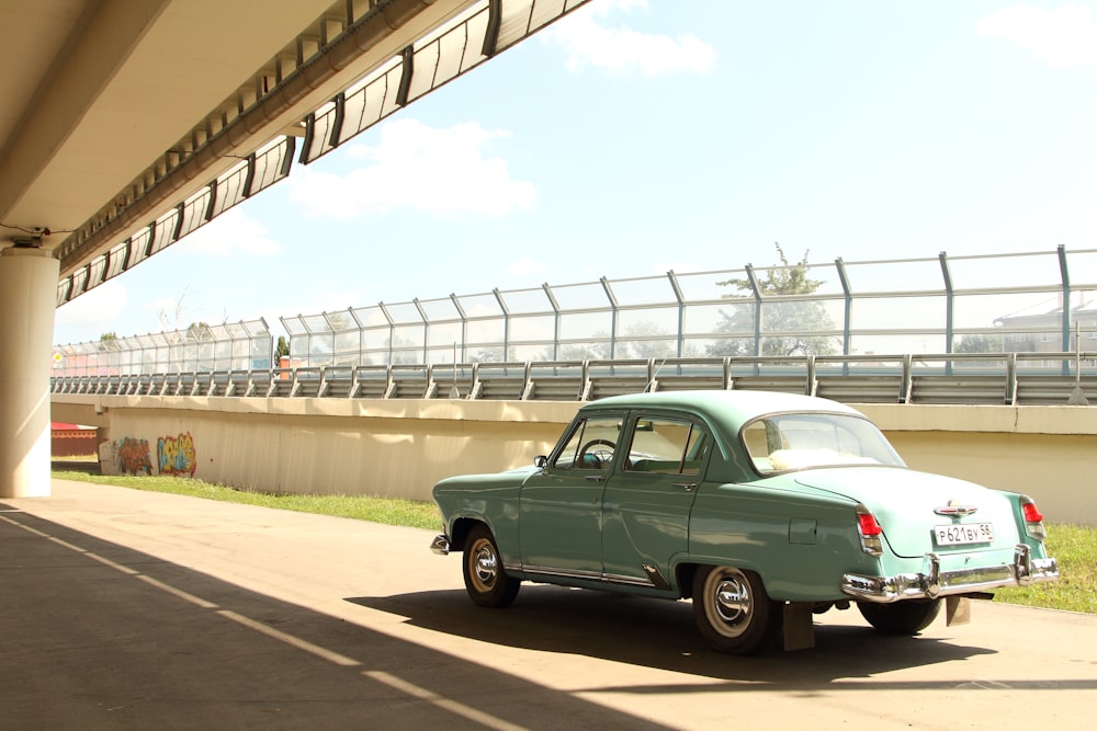 classic teal sedan passing by road