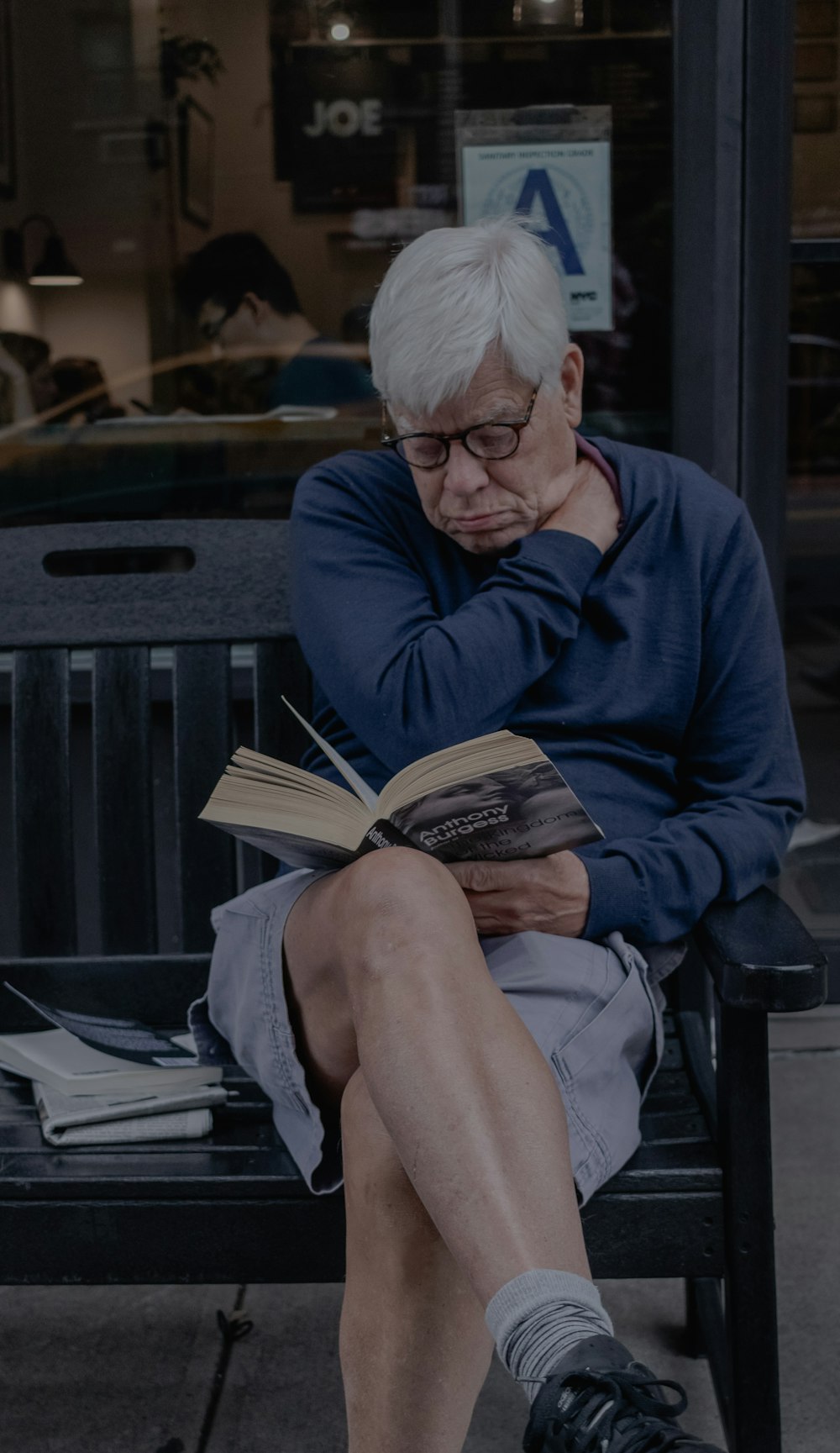 man sitting on bench while reading book