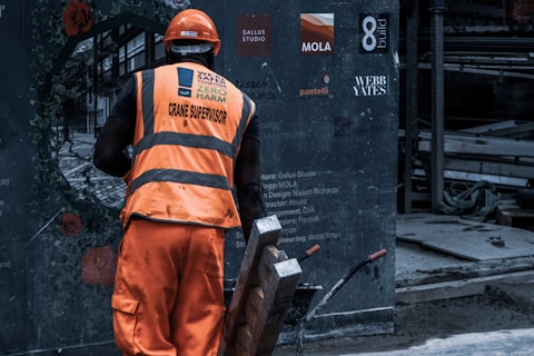 man in orange safety vest holding metal