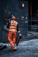 man in orange safety vest holding metal