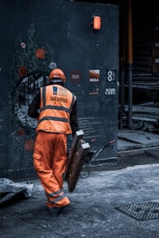 man in orange safety vest holding metal
