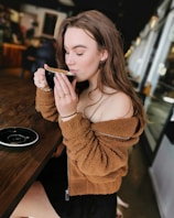 A relaxed woman in comfortable fashion, sipping coffee at a cozy cafe.
