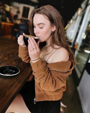 A relaxed woman in comfortable fashion, sipping coffee at a cozy cafe.