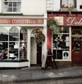 the front of a coffee shop with a woman sitting in the window