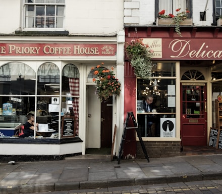 the front of a coffee shop with a woman sitting in the window