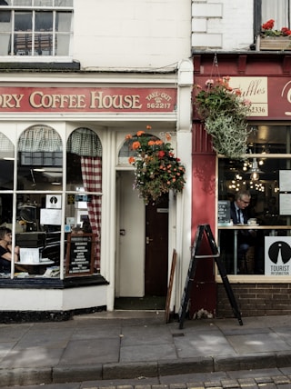 the front of a coffee shop with a woman sitting in the window