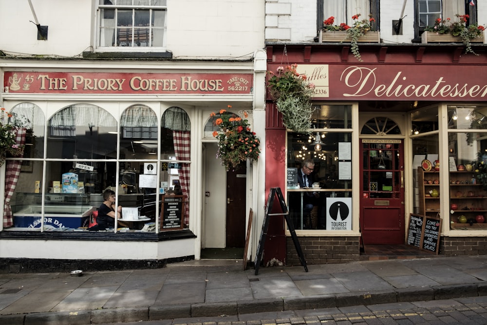 the front of a coffee shop with a woman sitting in the window