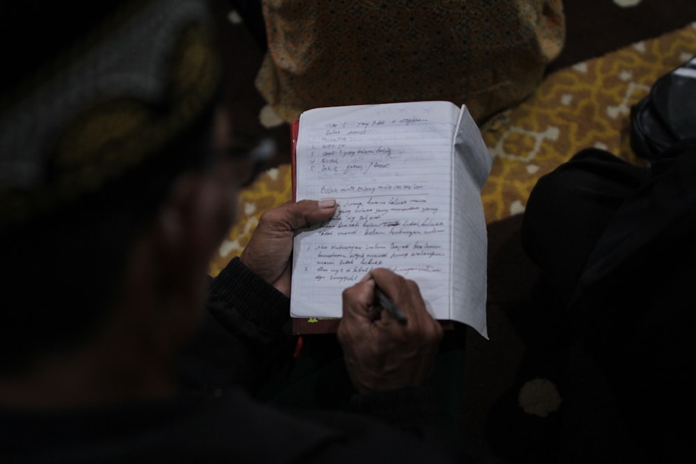 a person holding a pen and writing on a piece of paper