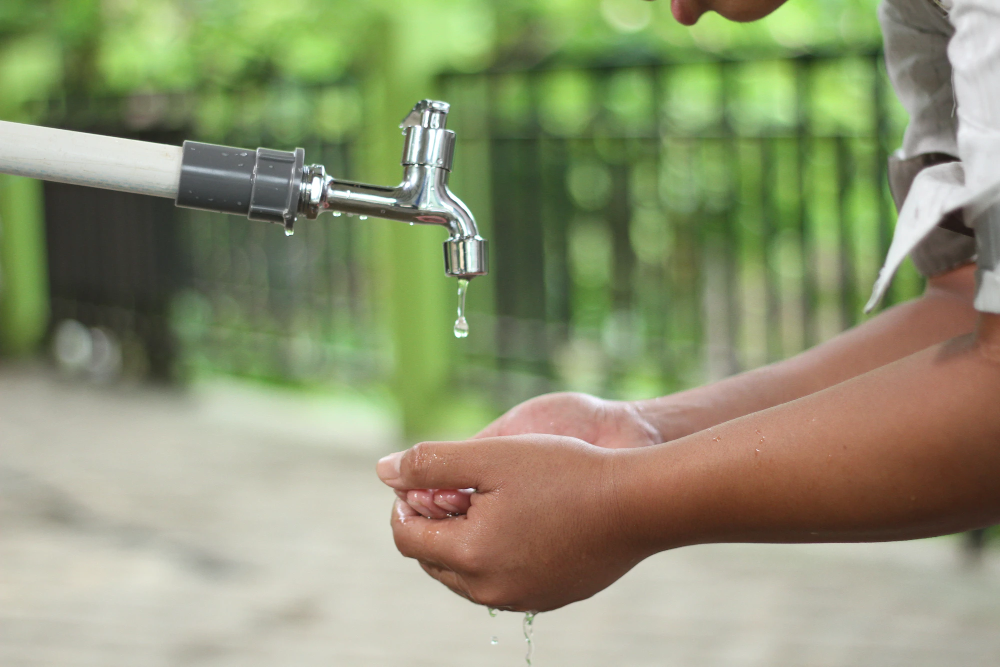 Hands washed under clean running water at an outdoor tap