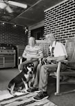 grayscale of man and woman sitting on wooden rocking chairs