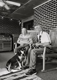 grayscale of man and woman sitting on wooden rocking chairs