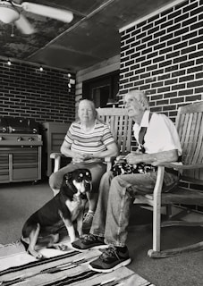 grayscale of man and woman sitting on wooden rocking chairs