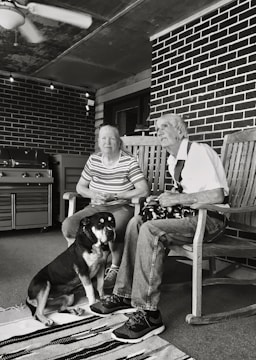 grayscale of man and woman sitting on wooden rocking chairs