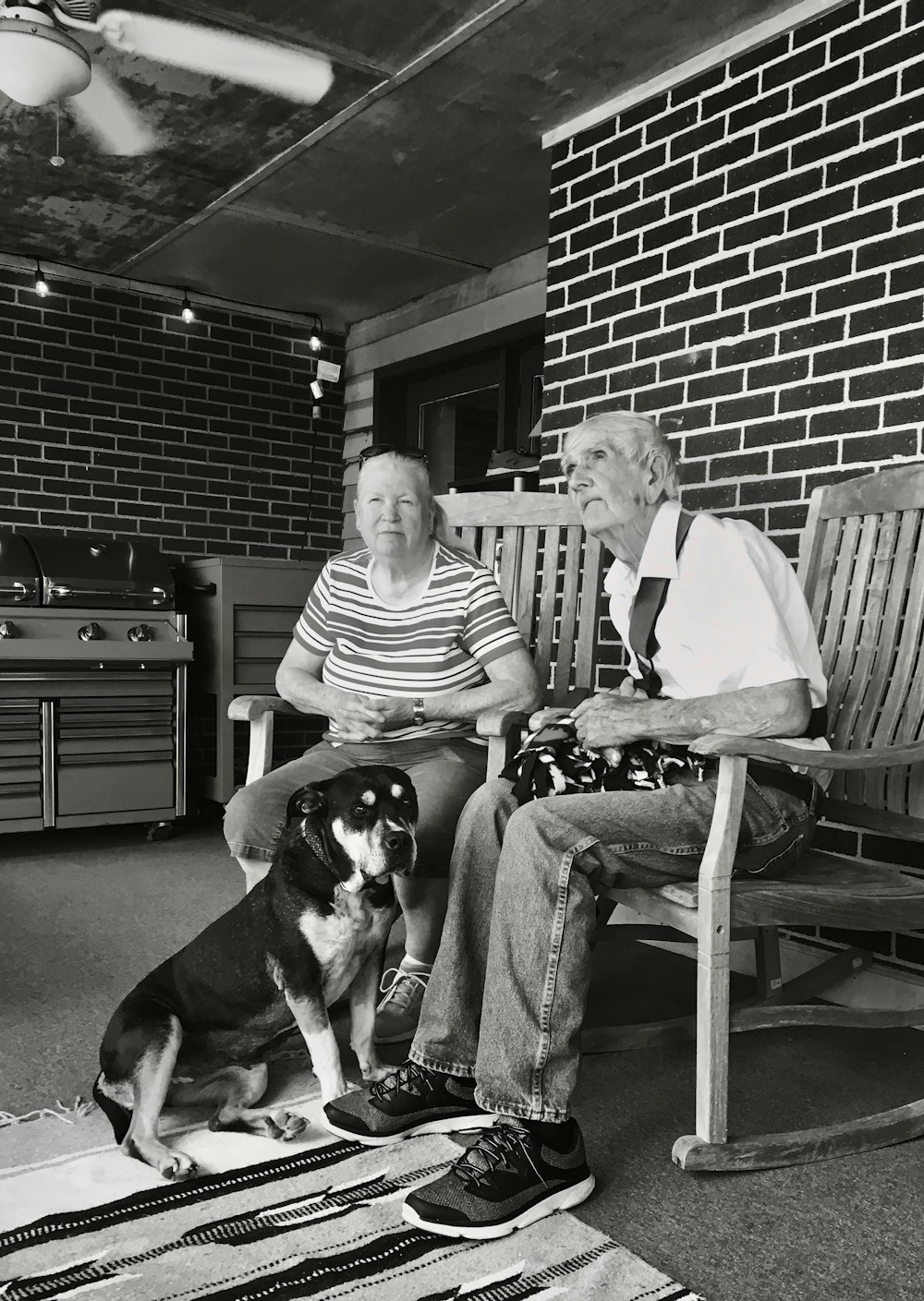 grayscale of man and woman sitting on wooden rocking chairs