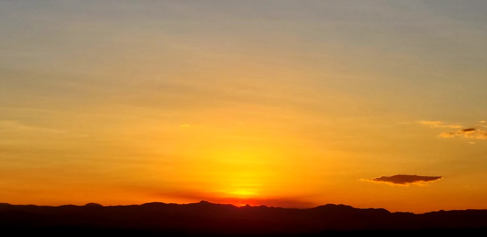 a plane flying in the sky at sunset