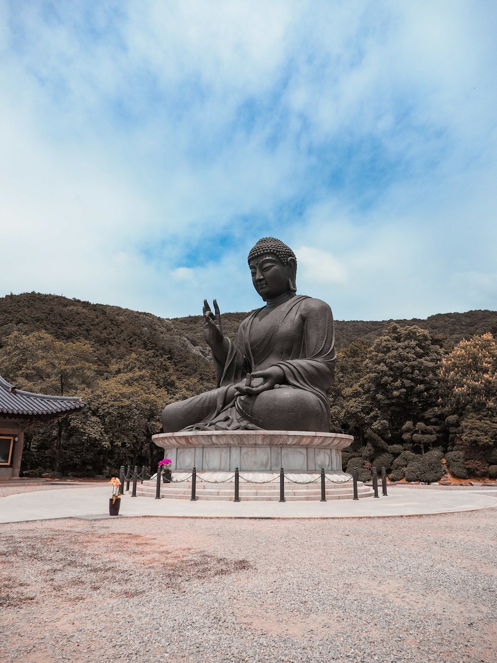 grey sitting buddha statue near hills under white cloudy sky