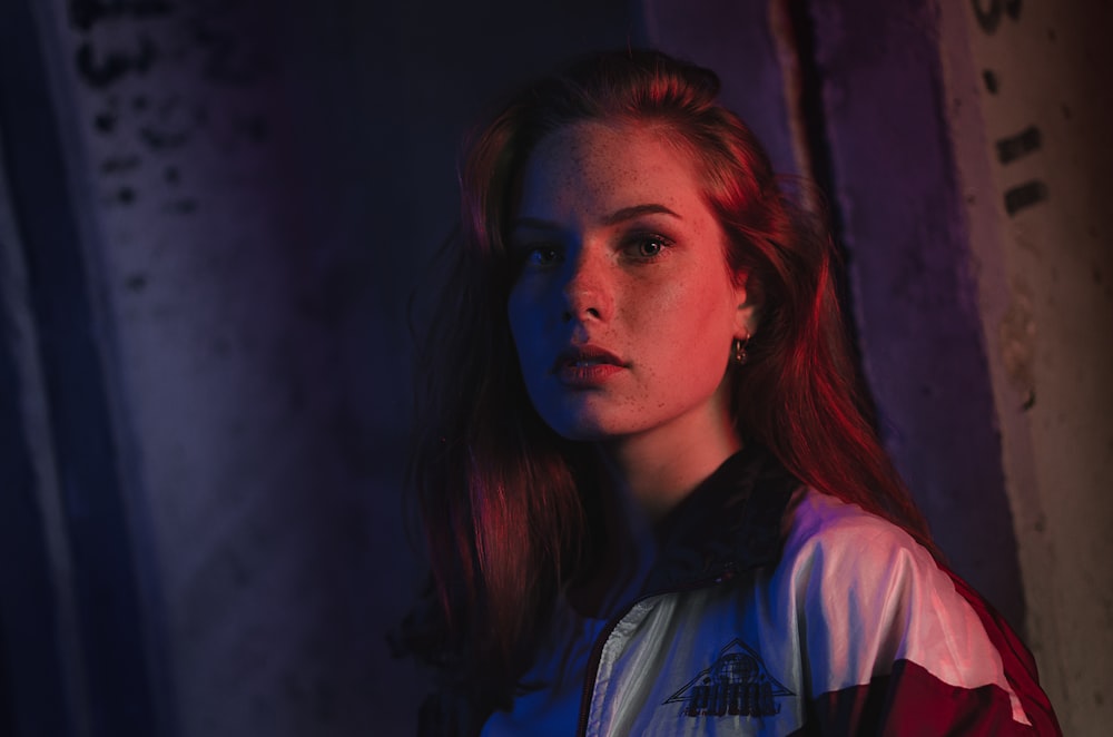 a woman with red hair standing in a dark room