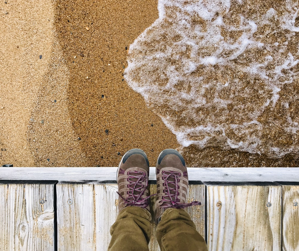 person standing on brown wooden dock