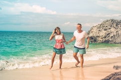 man and woman walking on seashore during daytime