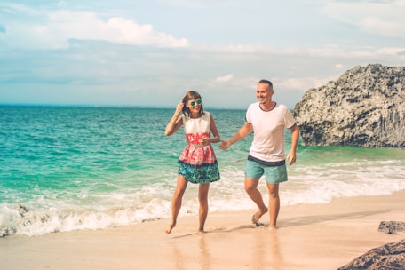 man and woman walking on seashore during daytime