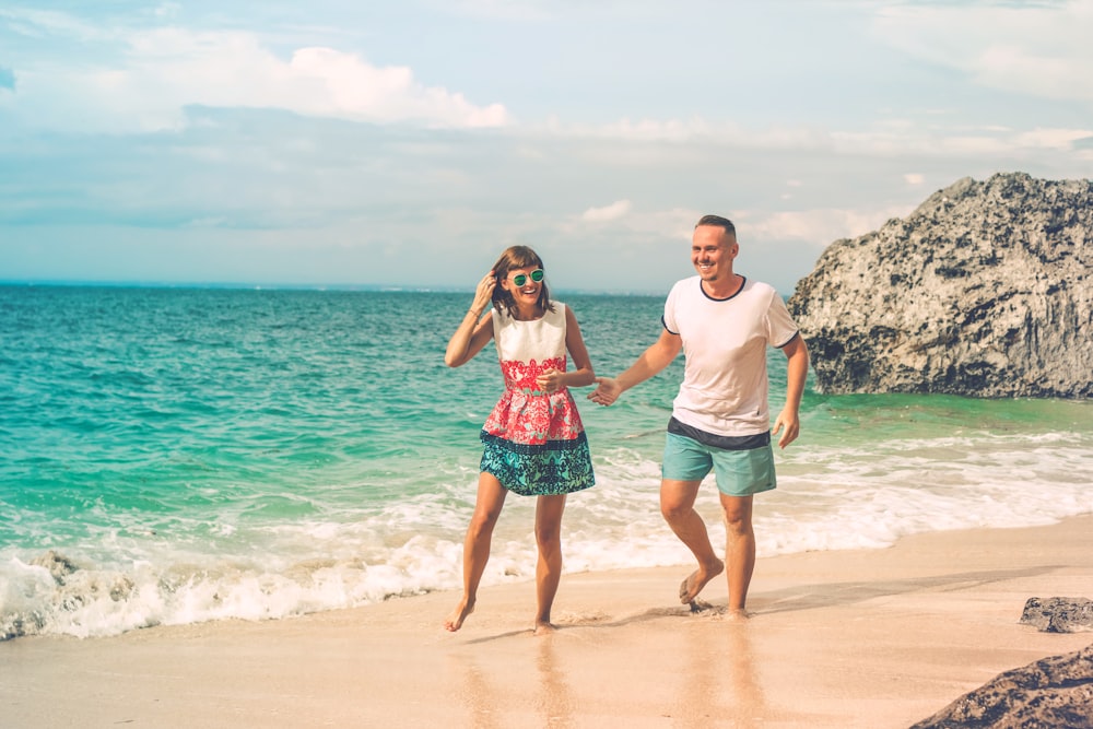 man and woman walking on seashore during daytime