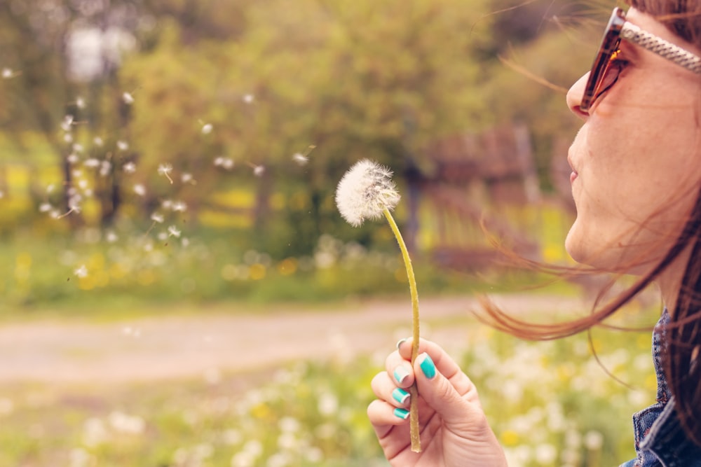 woman blowing dandelion flower