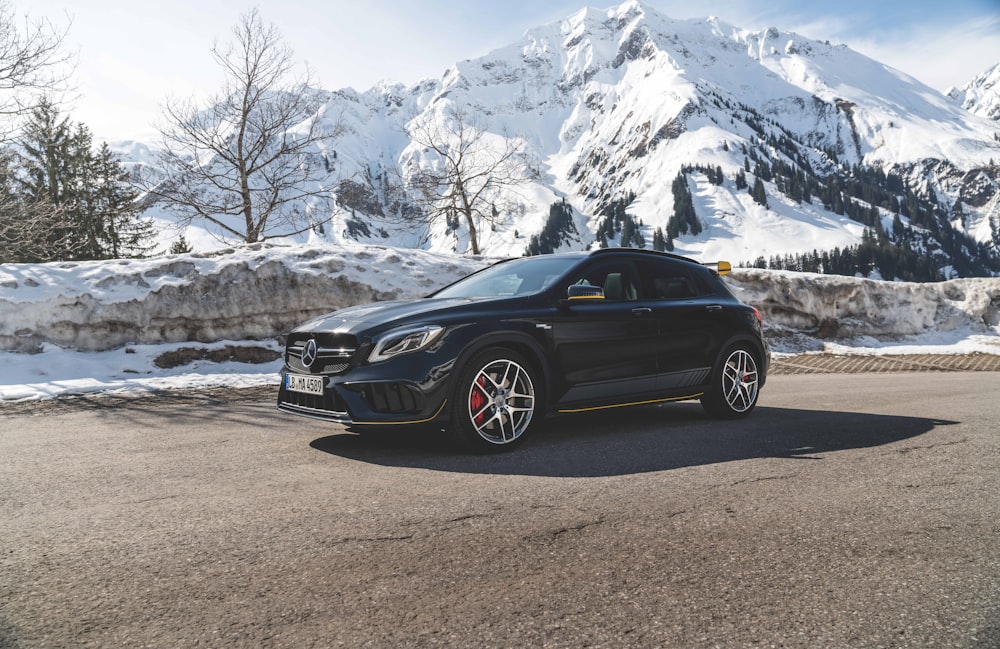 black Mercedes Benz 5-door hatchback on road beside mountain