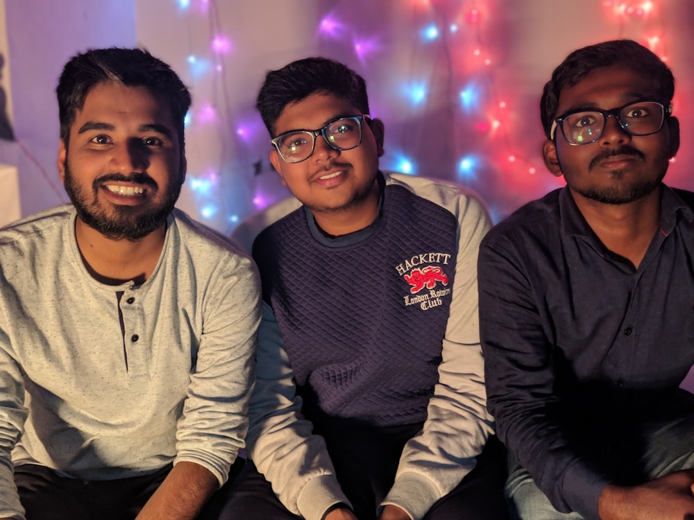 three men sits behind lighted wall