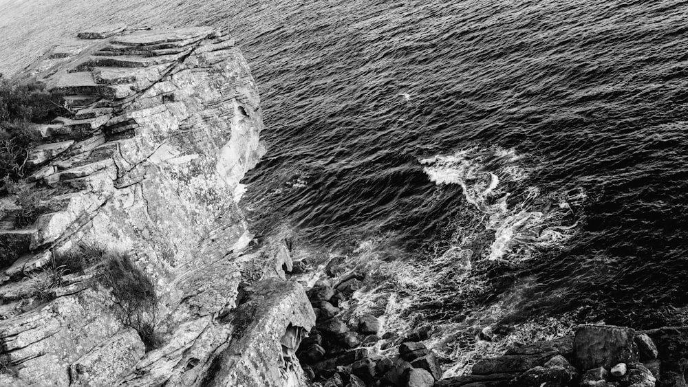 aerial grayscale photography of waves splashing on rock walls