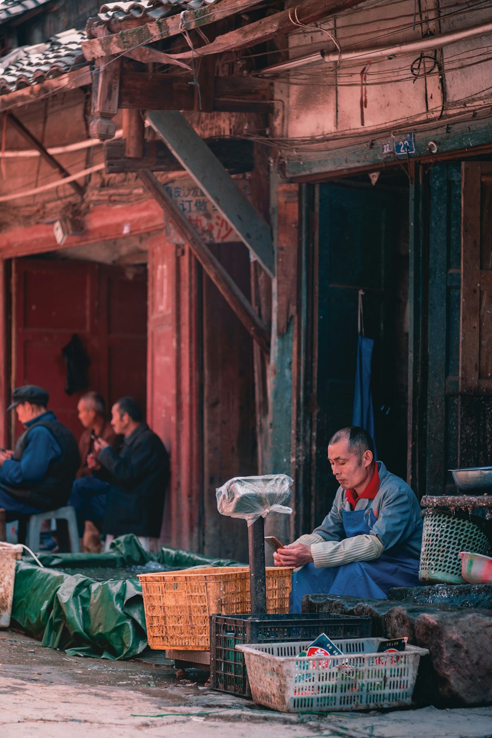 man sitting near crates and scale