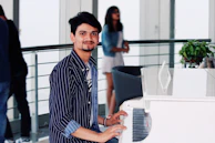 A young student smiling while playing a grand piano during a lesson.